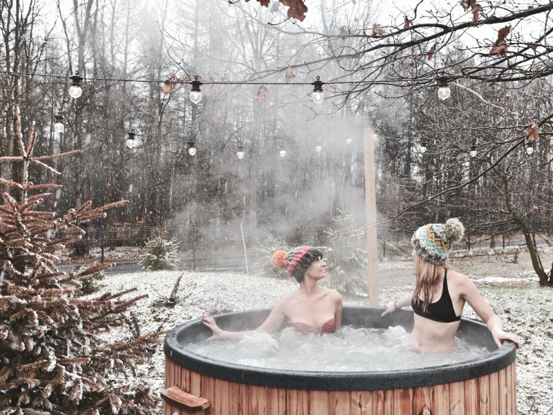 Kobiety relaksujące się w drewnianym jacuzzi ogrodowym zimą